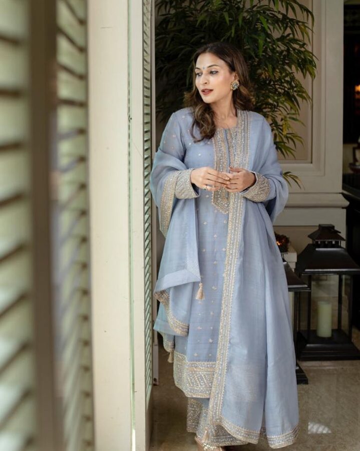 Aishwarya Rajinikanth standing in a doorway in a pale blue and silver anarkali