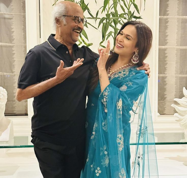 Aishwarya Rajinikanth in a blue embroidered outfit laughing with her father Rajinikanth