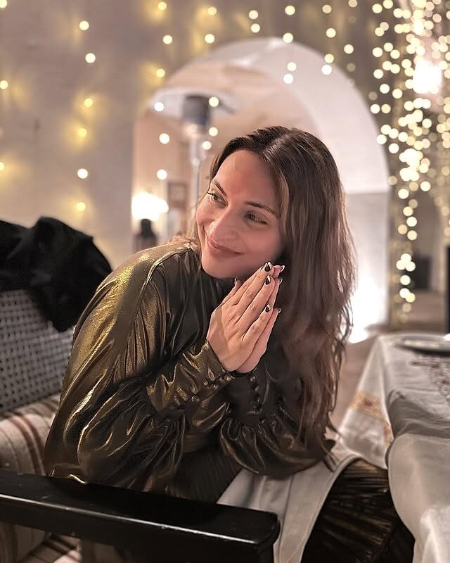 Aishwarya Rajinikanth photographed indoors in the evening, warm string lights behind her
